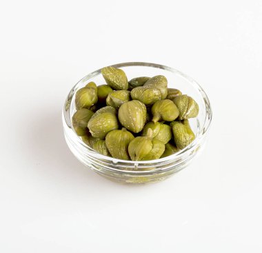 Beyaz arka planda izole edilmiş şeffaf bir kasede kapari.