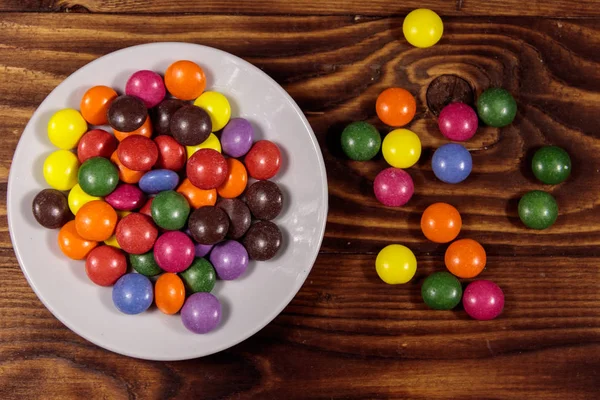 Untertasse Mit Bunten Knöpfchenförmigen Bonbons Gefüllt Mit Schokolade Auf Holztisch — Stockfoto