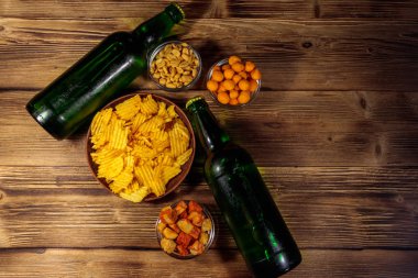 Bira şişeleri ve ahşap masada bira için çeşitli atıştırmalıklar. Üst görünüm