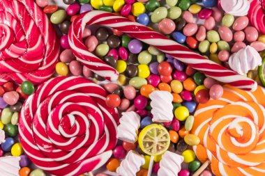 Renkli çikolata şekerlemeleri, lolipoplar, şeker kamışı ve şekerlemelerin arka planı