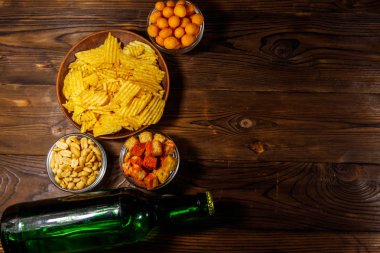 Bira şişeleri ve ahşap masada bira için çeşitli atıştırmalıklar. Üst görünüm, alanı kopyala