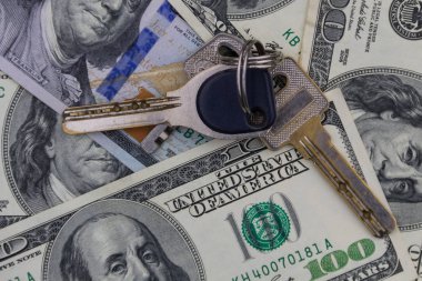 Yüz dolarlık banknotların arka planında anahtar var. Ev alma veya kiralama kavramı