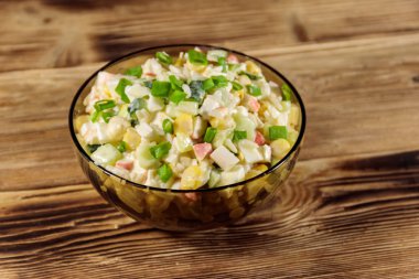 Yengeç çubuklu salata, mısır, salatalık, yumurta, pirinç ve mayonez ahşap masada.