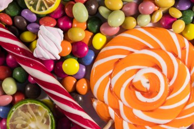 Renkli çikolata şekerlemeleri, lolipoplar, şeker kamışı ve şekerlemelerin arka planı