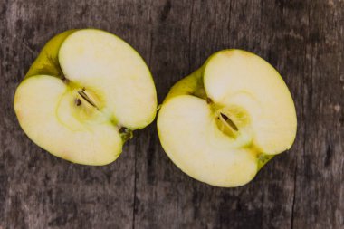 Rustik ahşap masa üzerinde yeşil elma yarısı. Üstten Görünüm