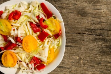 Lahanalı taze sebze salatası, sarı domates ve kırsal ahşap masada kırmızı tatlı biber. Üst görünüm