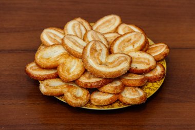 Heva bisküvi - Fransız çerezleri (aynı zamanda palmiye yaprakları, fil kulakları denilen veya kupa Fransız) puf böreği ahşap masa bir tabağa yapılan