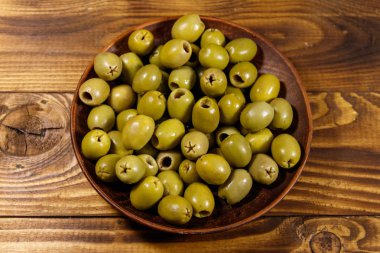 Ahşap masa üzerinde yeşil zeytin ile plaka