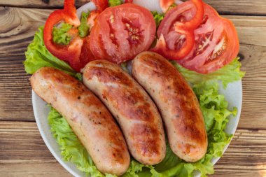 Ahşap masa üzerinde taze sebze ile ızgara sosis. Üstten görünüm