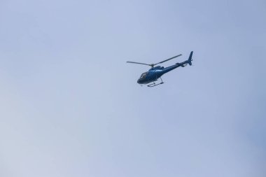 Mavi gökyüzünde uçan helikopter.