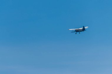 Mavi gökyüzünde uçan çift kanatlı uçak