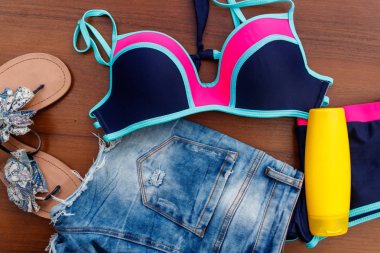 Ahşap arka plan üzerinde beachwear kümesi. Güneş kremi, Mayo, şort ve parmak arası terlik. Yaz tatil kavramı