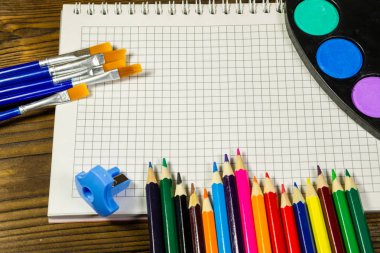 Ahşap arka plan üzerinde çizim araçları kümesi. Defter, suluboya boya, Boya fırçaları, boş renk masada kalemleri