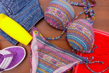 Ahşap arka plan üzerinde beachwear kümesi. Güneş kremi, havlu, Mayo, şort ve parmak arası terlik. Yaz tatil kavramı