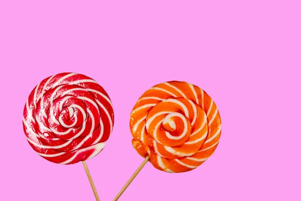 Red and orange lollipops on pink background