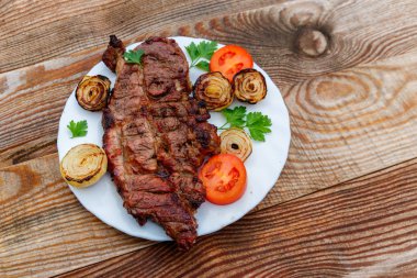Izgara domuz etli soğan, domates ve maydanoz ahşap masa üzerinde beyaz plaka