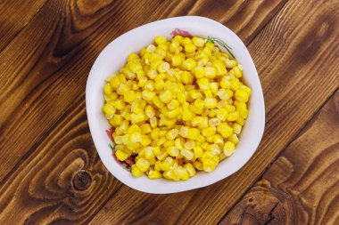 Ahşap masa üzerinde bir kase konserve mısır