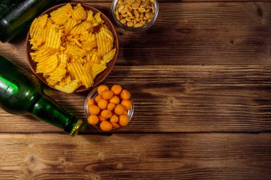 Bira şişeleri ve ahşap masada bira için çeşitli atıştırmalıklar.