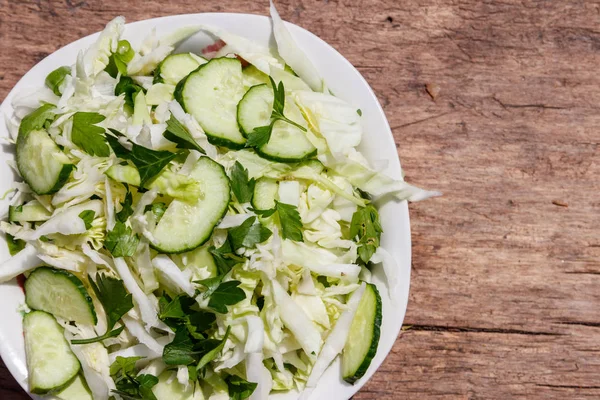 Bahar vegan salata lahana, salatalık, yeşil soğan ve maydanoz ahşap masa üzerinde. Üstten görünüm