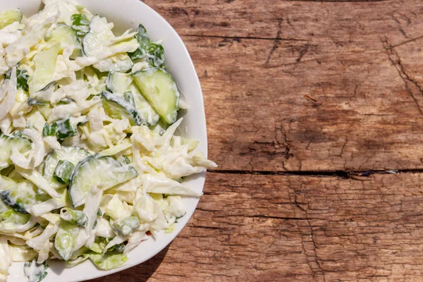 Spring salad with cabbage, cucumber, green onion, parsley and mayonnaise on wooden table. Top view — Stock Photo, Image