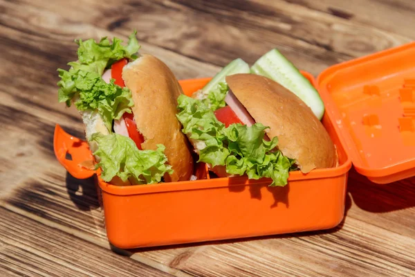 School lunch box with two homemade burgers and fresh cucumbers — Stock Photo, Image