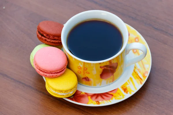 Cup of coffee with tasty colorful macarons on wooden table — Stock Photo, Image