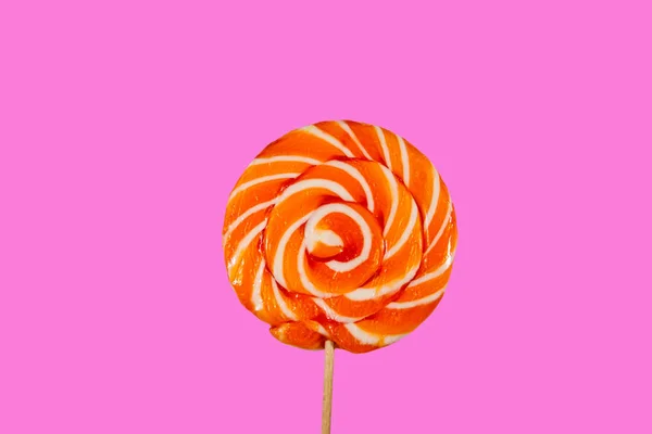 Pirulito de laranja doce no fundo rosa — Fotografia de Stock