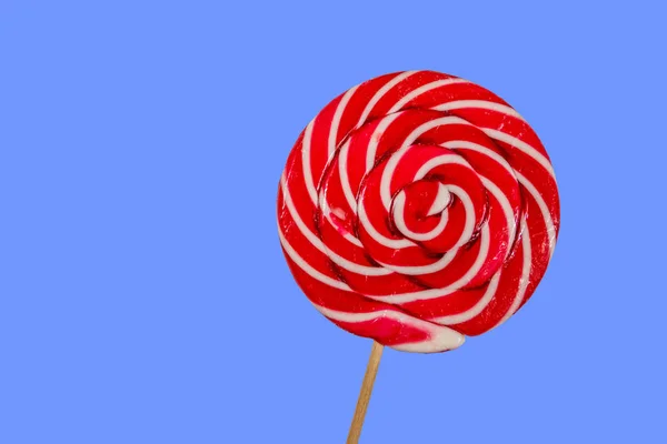 Sweet red lollipop on blue background