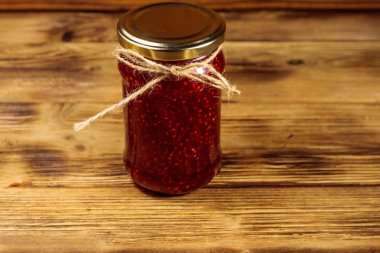 Ahşap masa üzerinde cam kavanozda ahududu reçeli