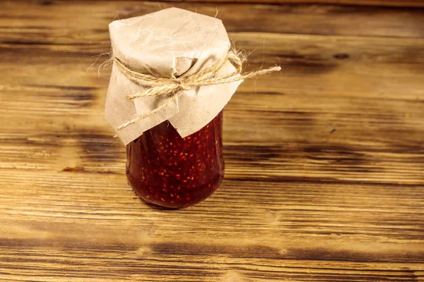 Selai raspberry dalam botol kaca di atas meja kayu — Stok Foto