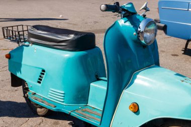 Şehrin caddesinde park etmiş mavi scooter.