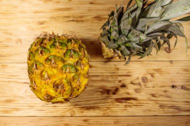 Ahşap masada ananas yaprakları ve meyvesi. Üstte görüntü
