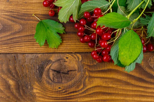 Ahşap masa üzerinde yeşil yaprakları ile kırmızı viburnum çilek. Üstte görüntü