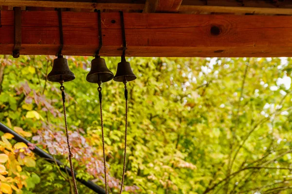 Три маленьких колокольчика висят на коричневых деревянных балках — стоковое фото
