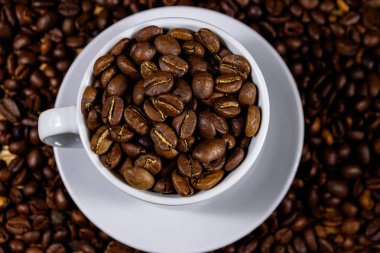 Kahve çekirdekleri arka planda beyaz fincan kavrulmuş kahve çekirdekleri