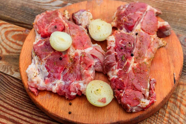 Carne fresca de cerdo cruda con especias y cebolla sobre tabla de cortar de madera —  Fotos de Stock
