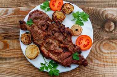 Beyaz tabakta soğan, domates ve maydanoz ile ızgara domuz eti 