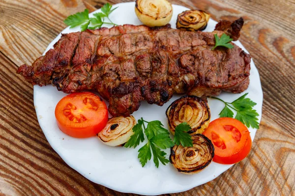 Beyaz tabakta soğan, domates ve maydanoz ile ızgara domuz eti 