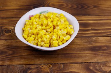 Ahşap masa üzerinde bir kase konserve mısır