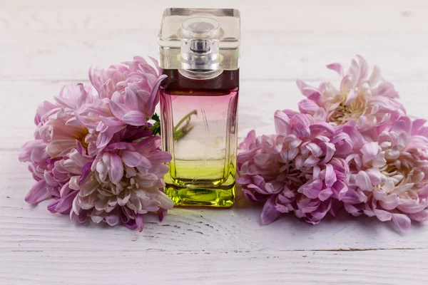 Femmes parfum avec des fleurs sur fond blanc en bois — Photo