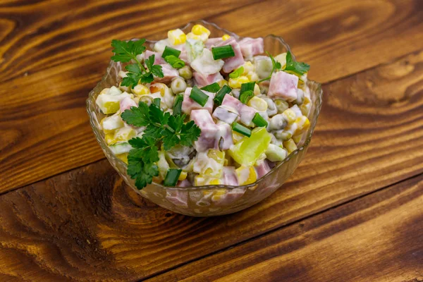 Вкусный салат с колбасой, зеленым горошком, консервированной кукурузой, перцем, огурцом и майонезом на деревянном столе — стоковое фото