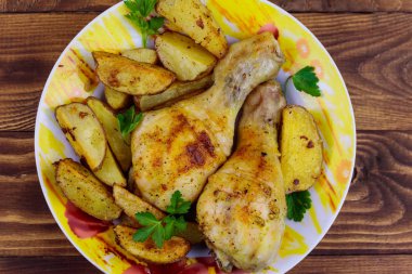 Ahşap masa üzerinde bir tabakta patates ile Fırında tavuk baget