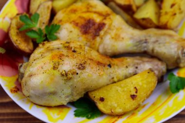 Ahşap masa üzerinde bir tabakta patates ile Fırında tavuk baget