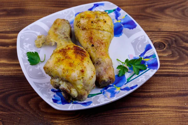 Gebakken kip drumsticks met aardappelen in een bord op houten tafel — Stockfoto