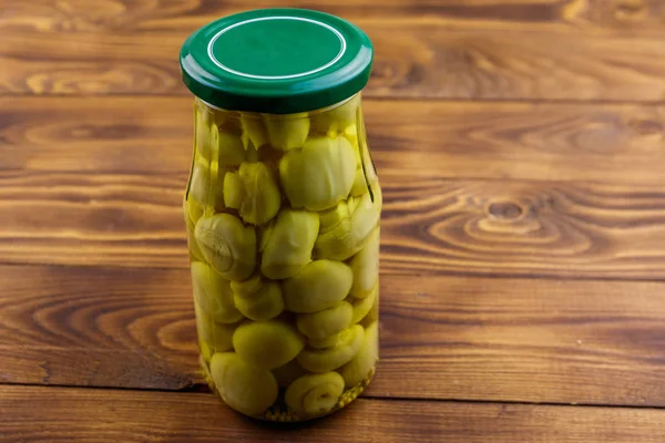 Delicious marinated mushrooms in glass jar on wooden table — Stock Photo, Image