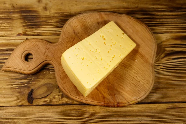 Kawałek sera na deska do krojenia na drewnianym stole — Zdjęcie stockowe