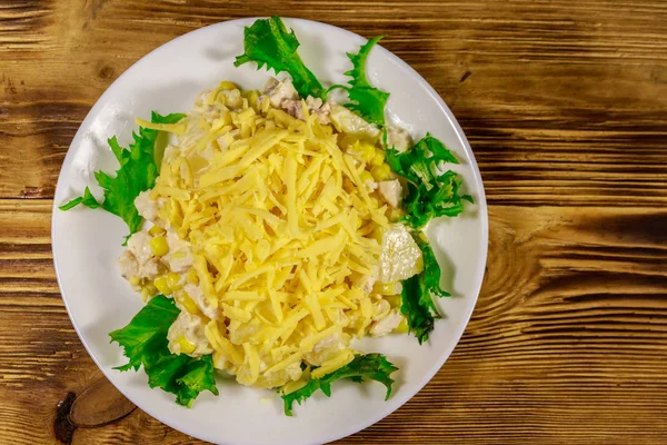 Праздничный салат с куриной грудью, сладкой кукурузой, консервированным ананасом, сыром и майонезом на деревянном столе — стоковое фото