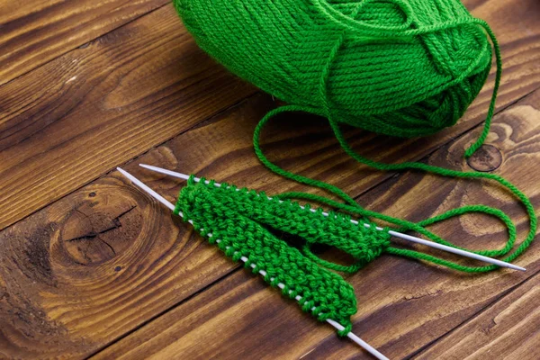 Balle de fil et aiguilles à tricoter avec tricot sur table en bois — Photo