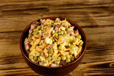 Sosis, bezelye, havuç ve soğan ahşap masa üzerinde mayonez salatası