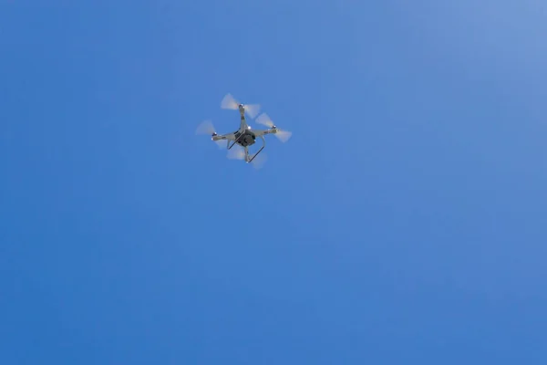 Quadcopter drone with the camera hovering in blue sky — Stock Photo, Image